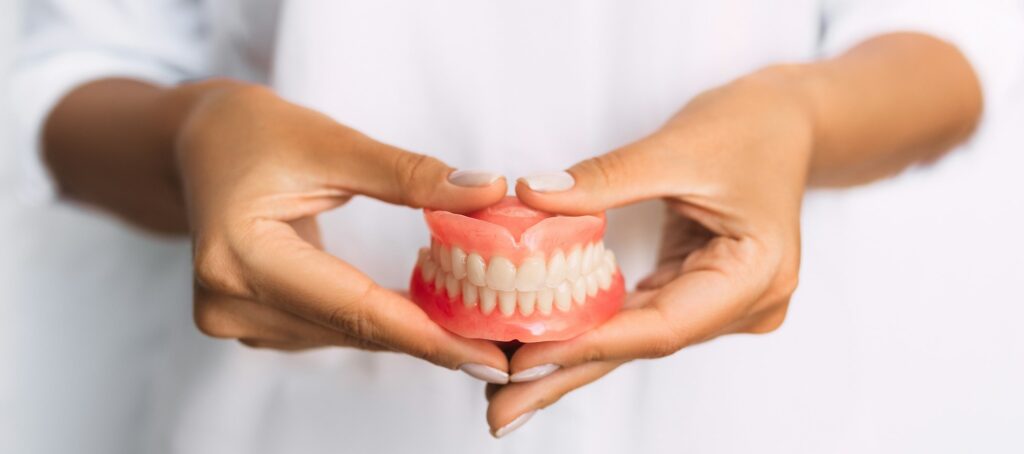 The dentist is holding dentures in his hands. Dental prosthesis in the hands of the doctor